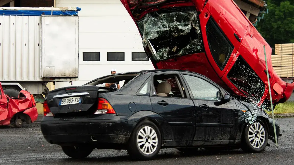 Red car overturned on black car in crash